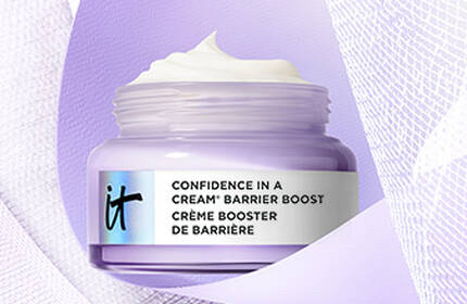 Jar of IT Cosmetics Confidence in a Cream Barrier Boost moisturizer with whipped texture, in a lavender container on a textured background.