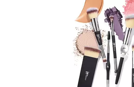IT Cosmetics makeup brushes with powder, blush, and eyeshadow swatches in peach, purple, and pink shades.