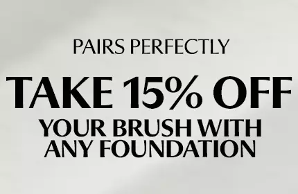IT Cosmetics makeup brushes with powder, blush, and eyeshadow swatches in peach, purple, and pink shades.