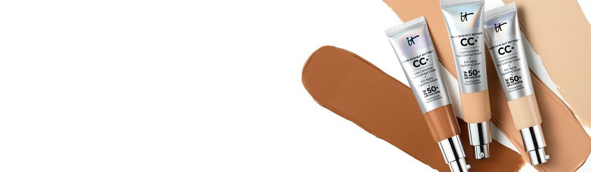 Partial view of IT Cosmetics CC+ Cream tube with deep shade foundation swatch in background.